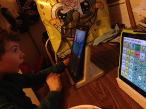 Bolin’s son, Finnegan, plays Wheel of Fortune on his iPad while a SpongeBob balloon looms in the background. His communication device screen reads “Mom wheel play with me.”