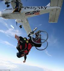 An individual in a wheelchair skydives out of an airplane.